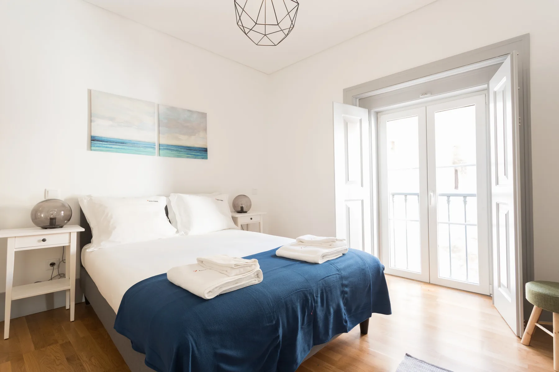 A bright bedroom with a bed and large windows opening onto a balcony.