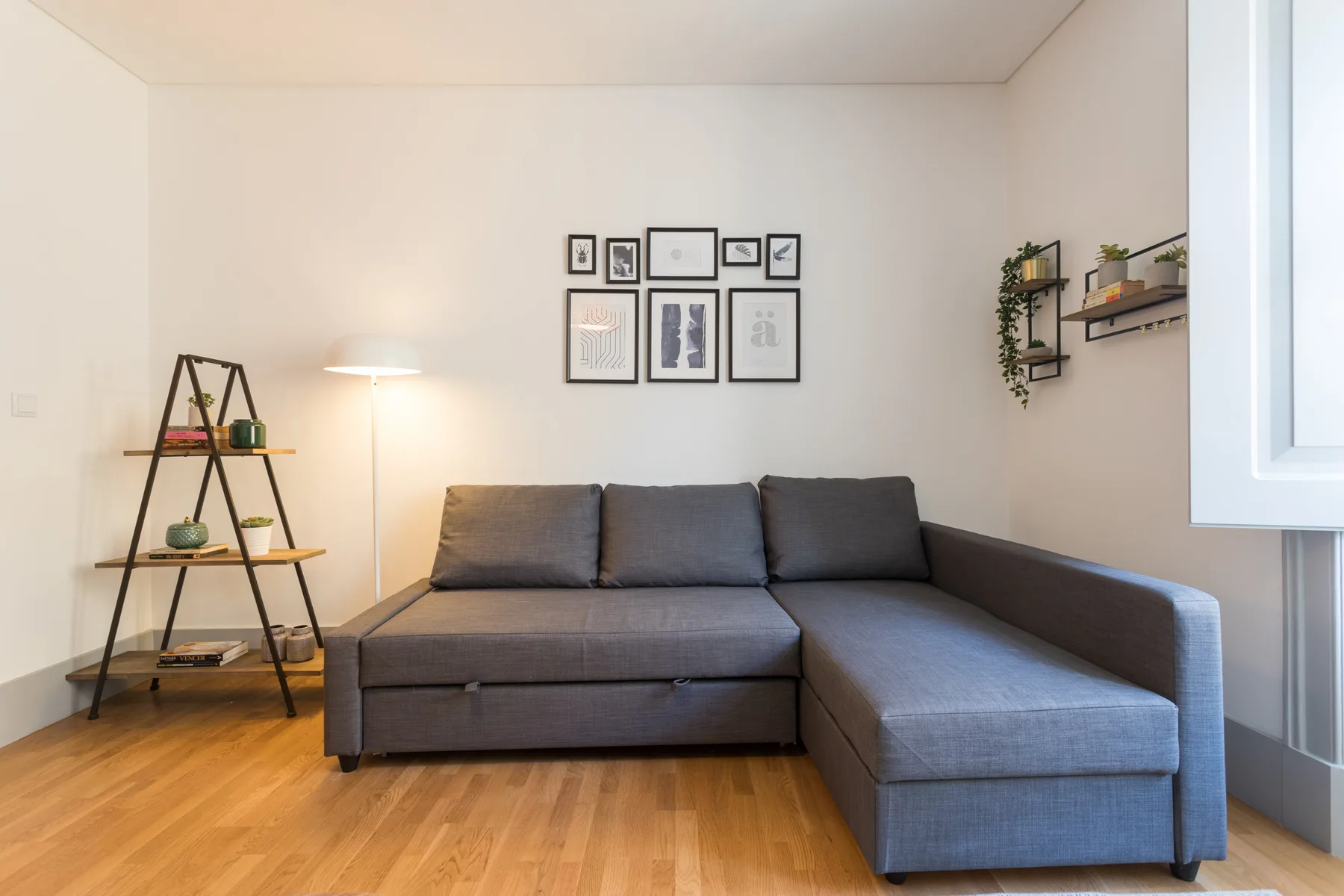 Una sala de estar con un sofá seccional gris y cuadros en la pared.
