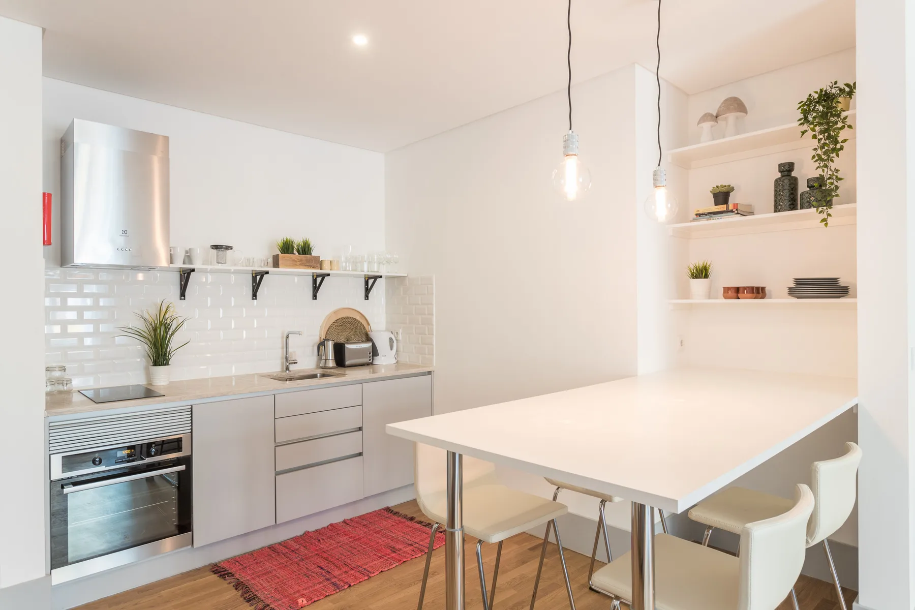 Una cocina y comedor luminosos con una encimera, asientos y estantes abiertos.