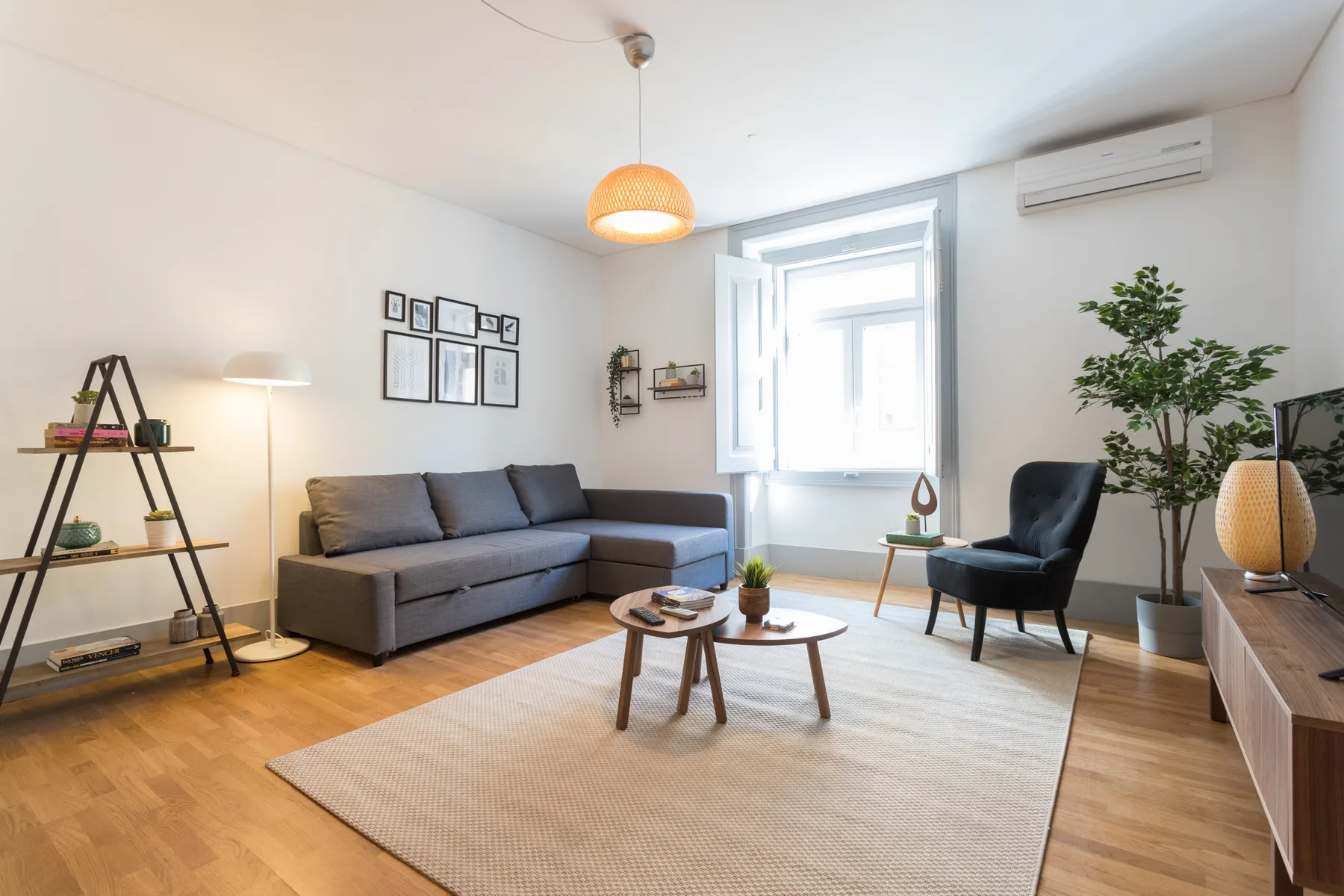 A bright living room with a gray sofa, armchair, and large window.