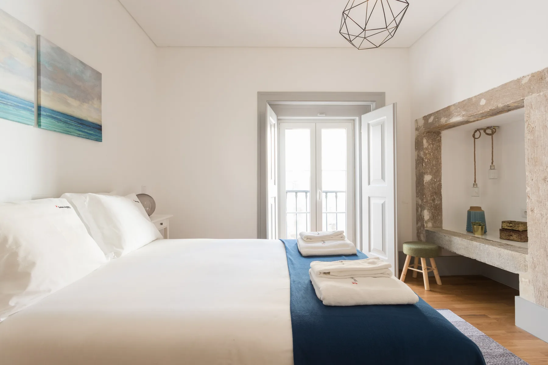 Un dormitorio luminoso con una cama ordenada y una ventana abierta.