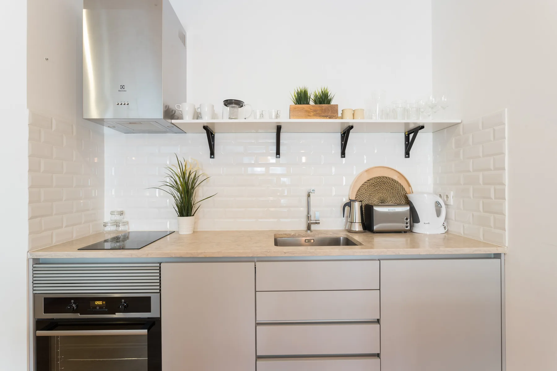 Una cocina compacta con encimera, fregadero y pequeños electrodomésticos.