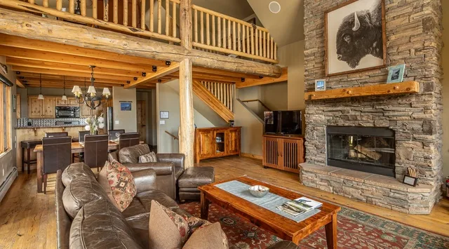 A rustic living room with leather seating and a stone fireplace.