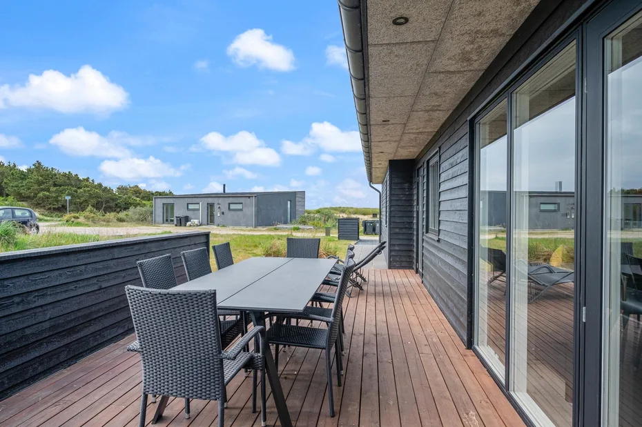 Una terraza exterior con una mesa de comedor y asientos junto a un edificio.