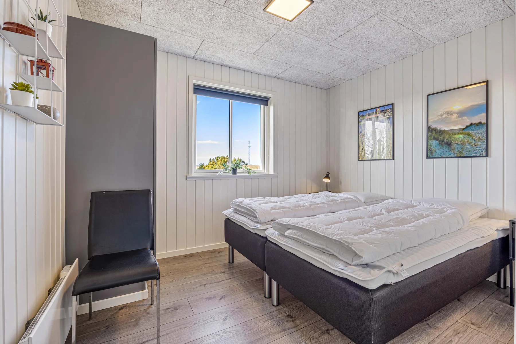 Un dormitorio con camas, una ventana y cuadros en la pared.
