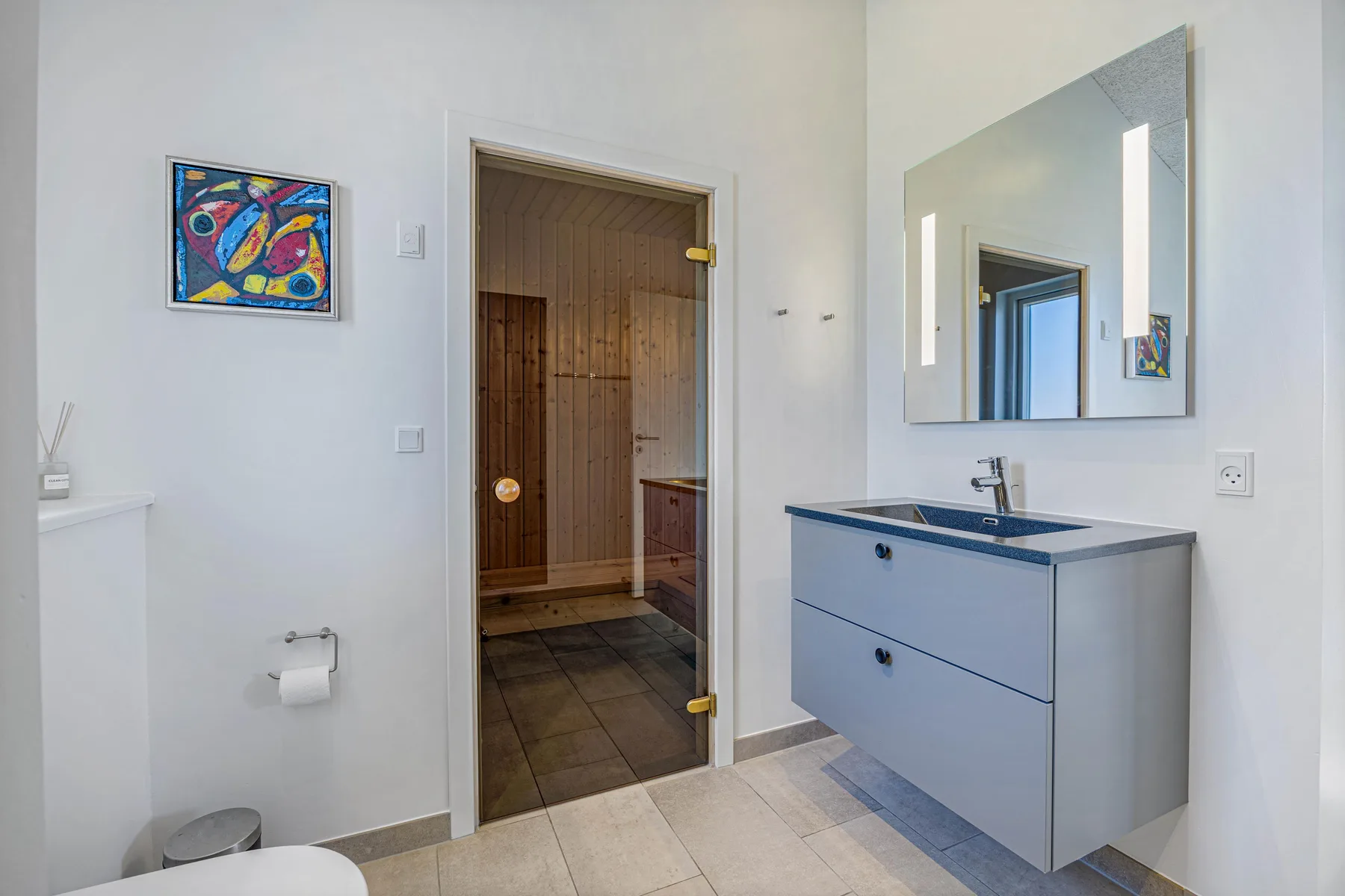 Un baño luminoso con lavabo, espejo de pared y una puerta abierta.