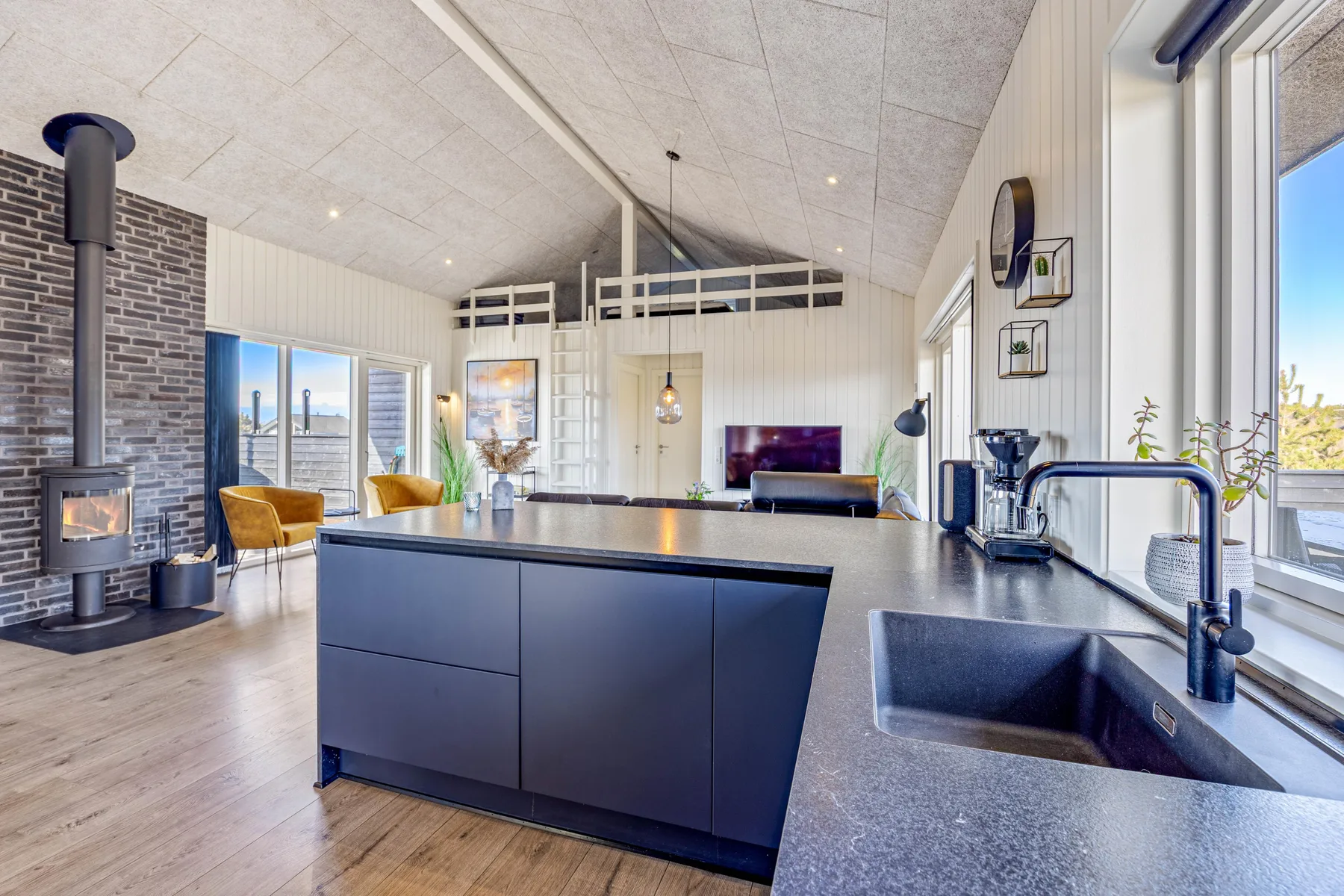 Una luminosa sala de estar de planta abierta con una isla de cocina y una chimenea.