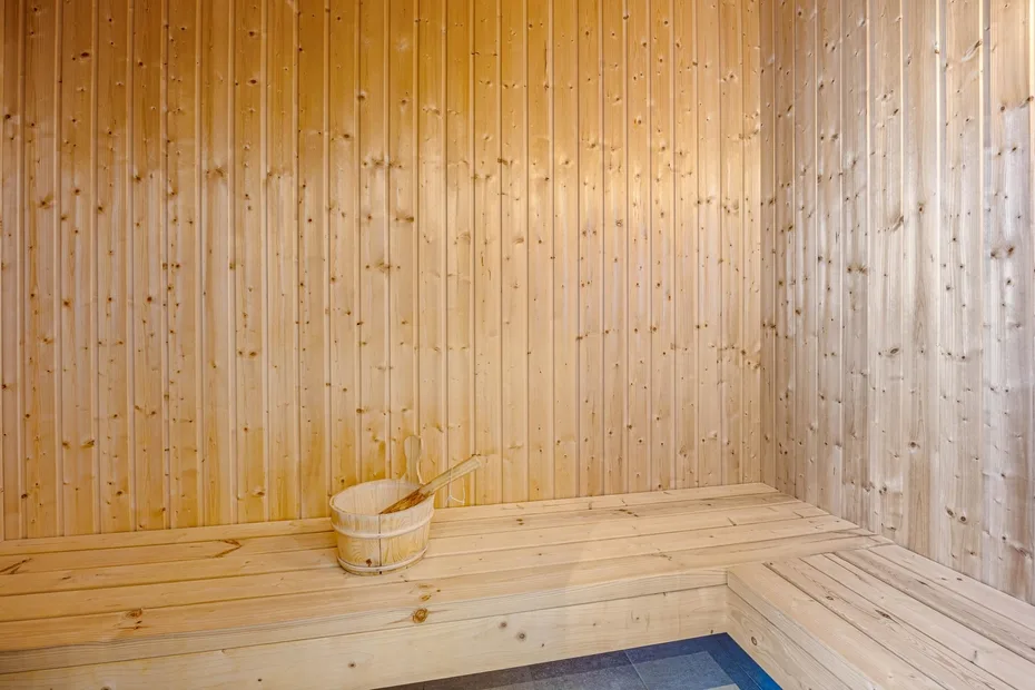 Una sauna revestida de madera con un banco y un cubo de madera.