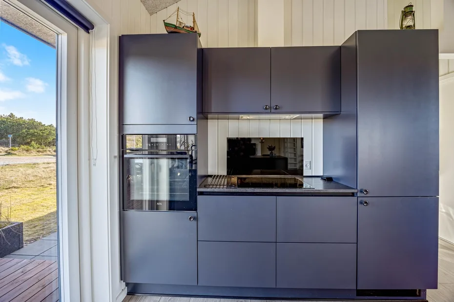 Una cocina moderna con gabinetes oscuros, horno y placa de cocina.