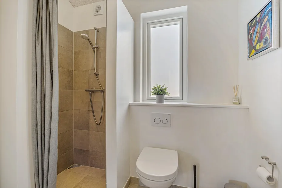 Un baño con ducha, inodoro y ventana.