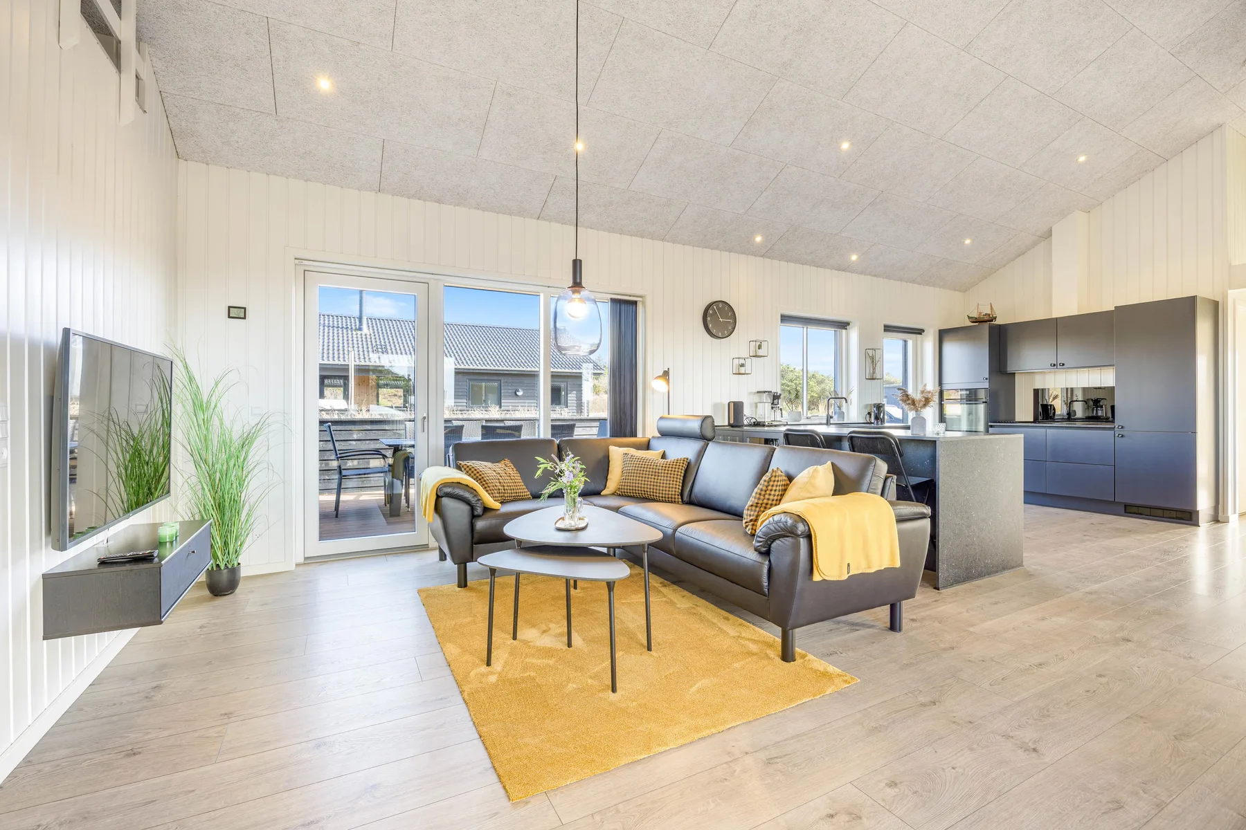 Sala de estar y cocina de planta abierta, con asientos junto a una ventana grande.