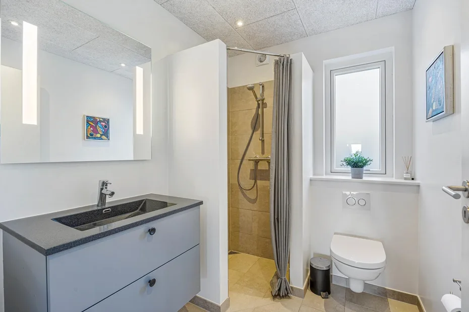 Un baño luminoso con lavabo, inodoro y ducha con cortina.