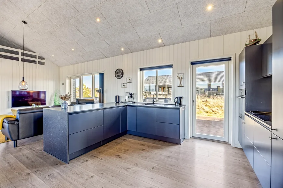 Una cocina moderna con gabinetes oscuros, una isla grande y puertas de vidrio.