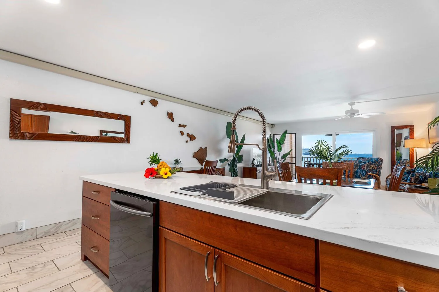 Una isla de cocina con fregadero y gabinetes de madera da a un comedor.