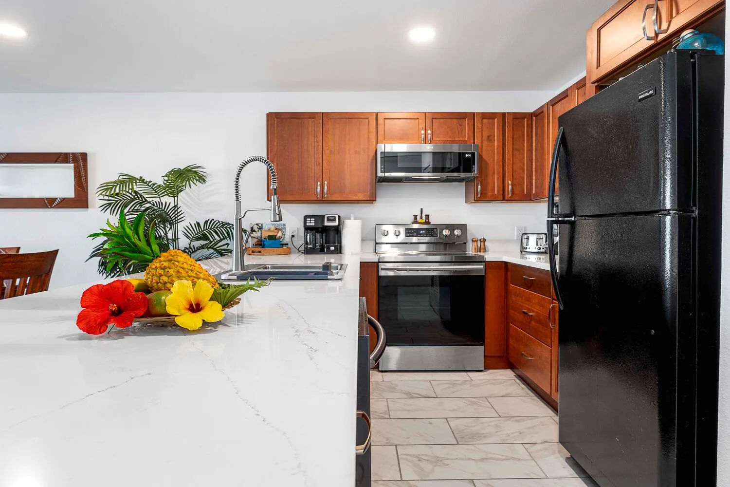 Una cocina con gabinetes de madera, electrodomésticos oscuros y una isla blanca.