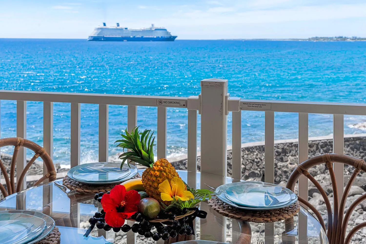 Un comedor junto al mar mira hacia aguas turquesas, con fruta sobre la mesa.