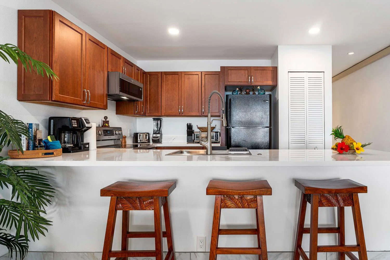 Una cocina con una isla blanca y asientos de madera.
