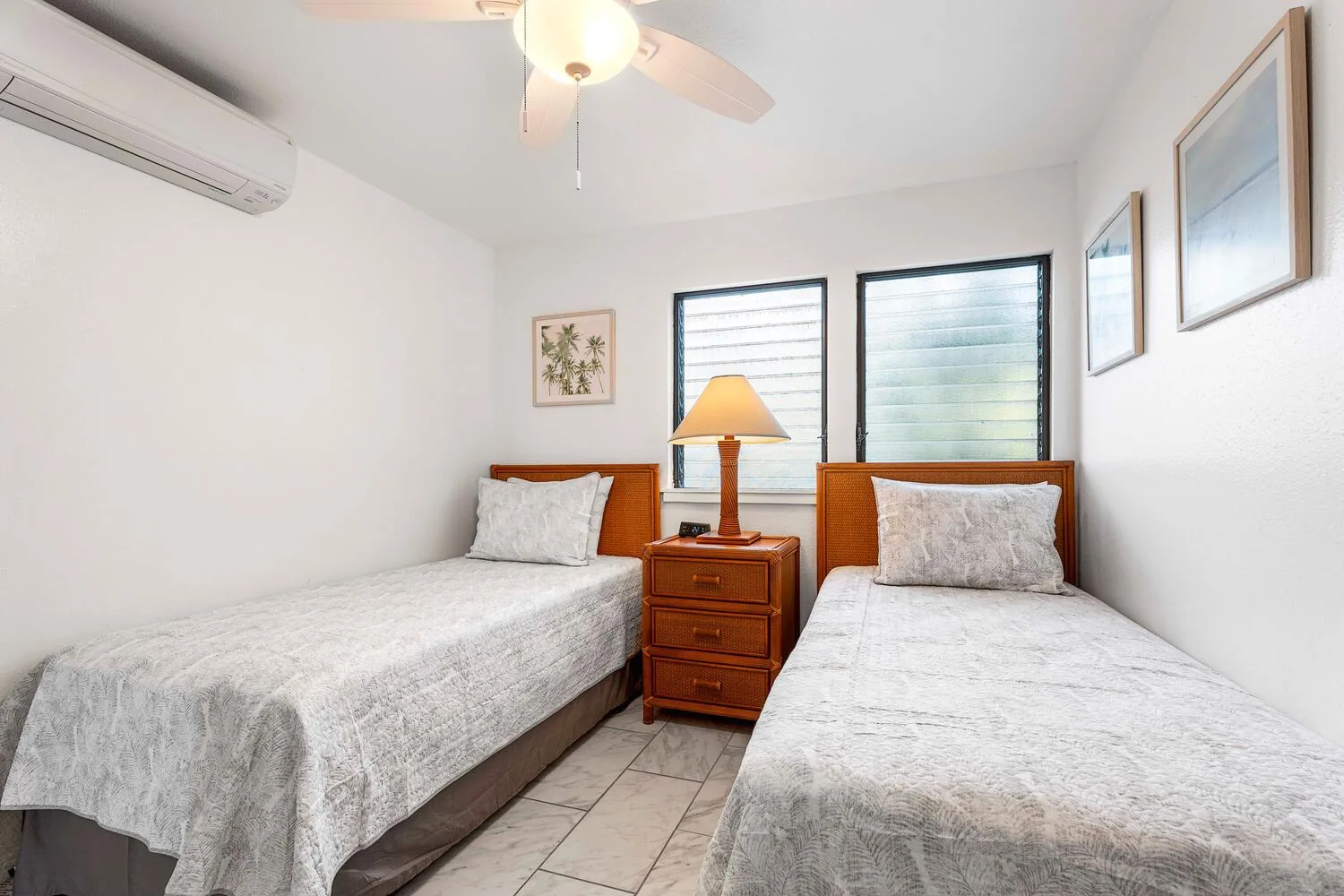Un dormitorio luminoso con dos camas y una mesita de noche.