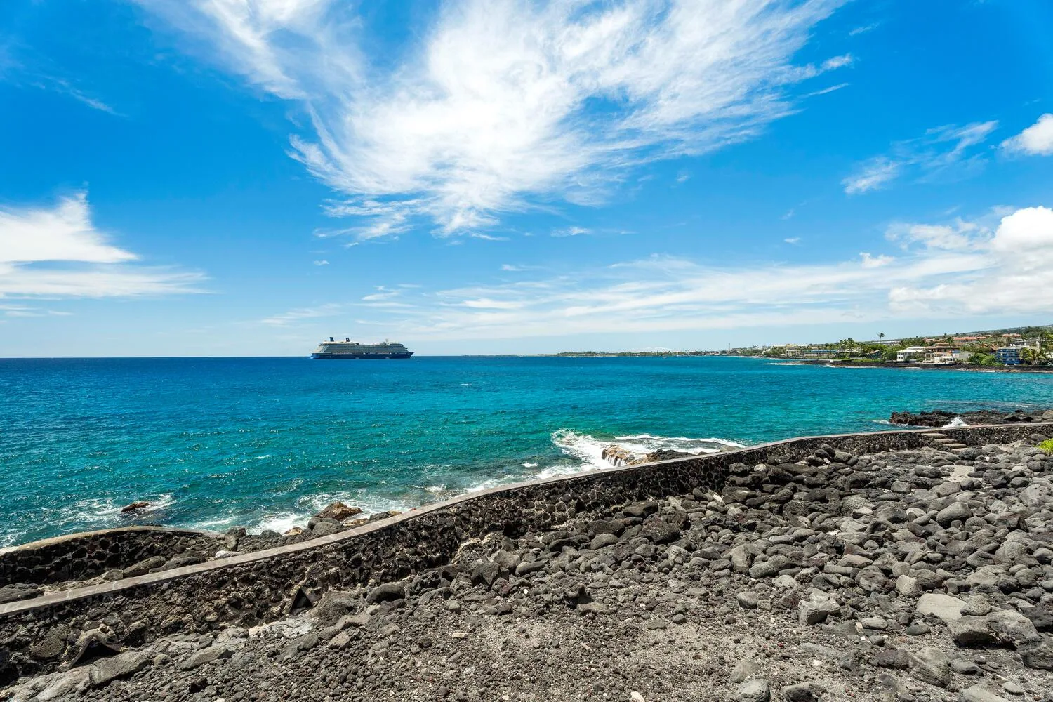 Una costa rocosa bordea aguas turquesas bajo un cielo azul.