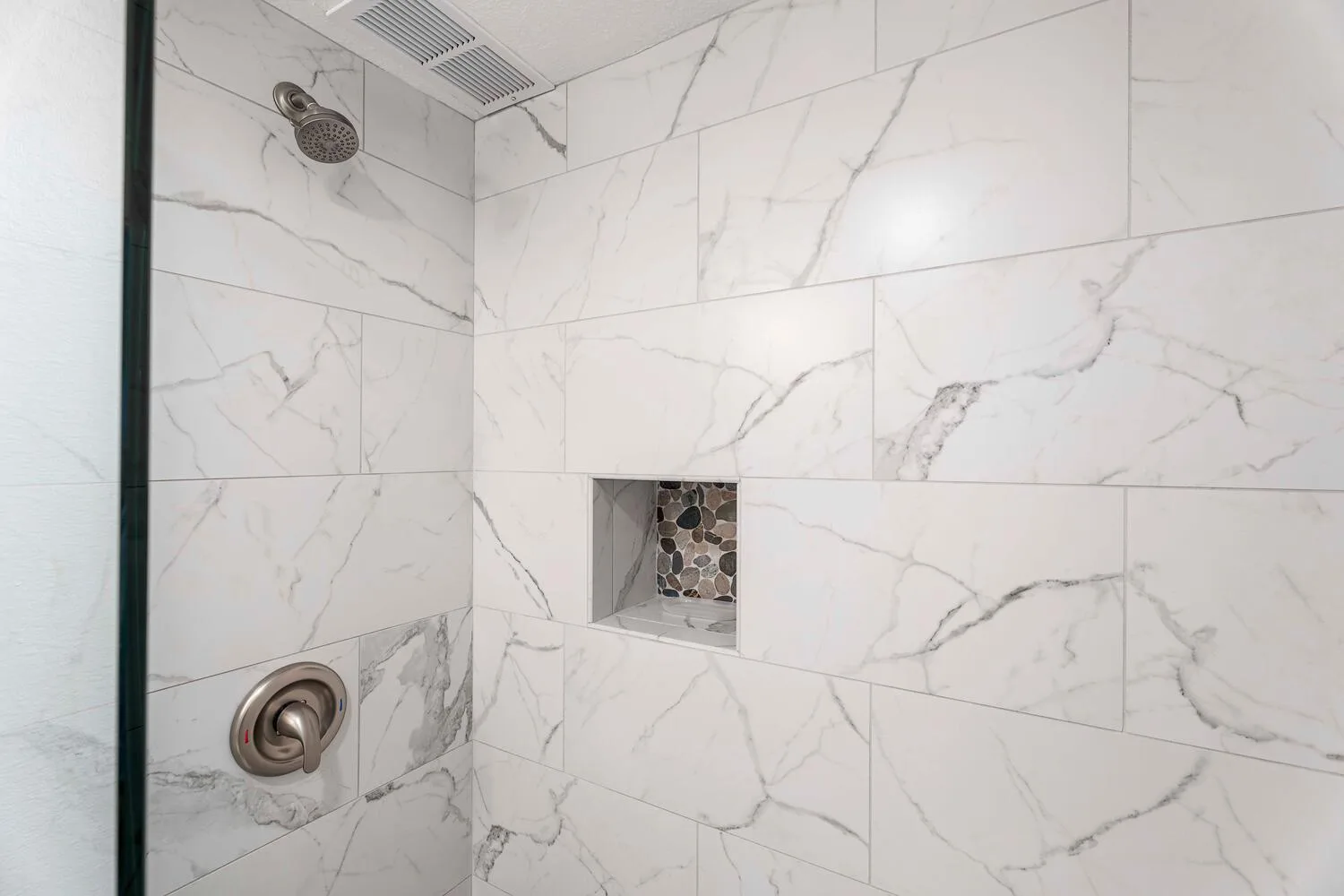 Una ducha revestida de azulejos con un nicho empotrado en la pared.
