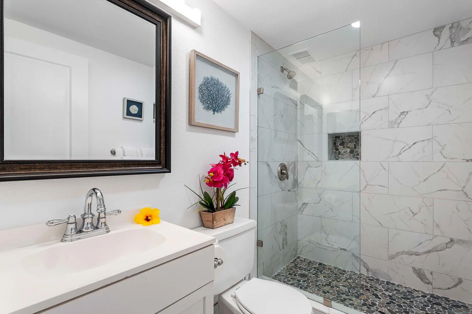 Un baño luminoso con lavabo, espejo y ducha de vidrio.