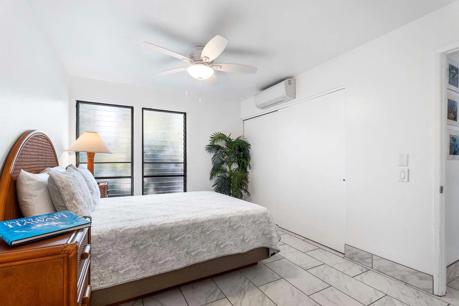 Un dormitorio luminoso con una cama, ventanas grandes y un ventilador de techo.