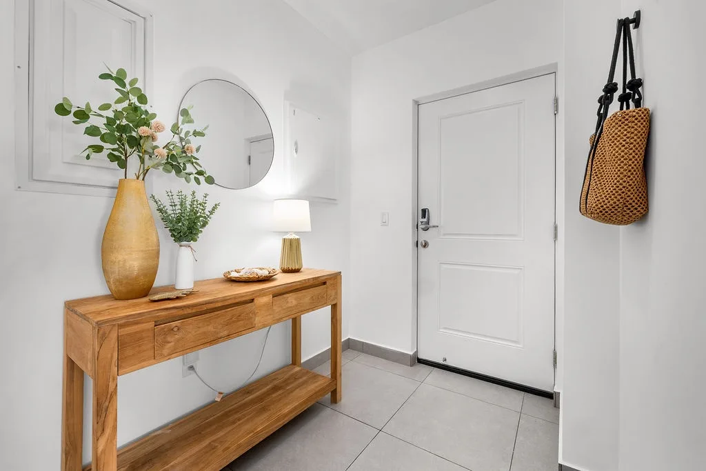 Step into your welcoming entryway, where warm wood tones and fresh greenery greet you. A thoughtfully styled console offers space for keys and belongings, while natural light creates an inviting atmosphere.