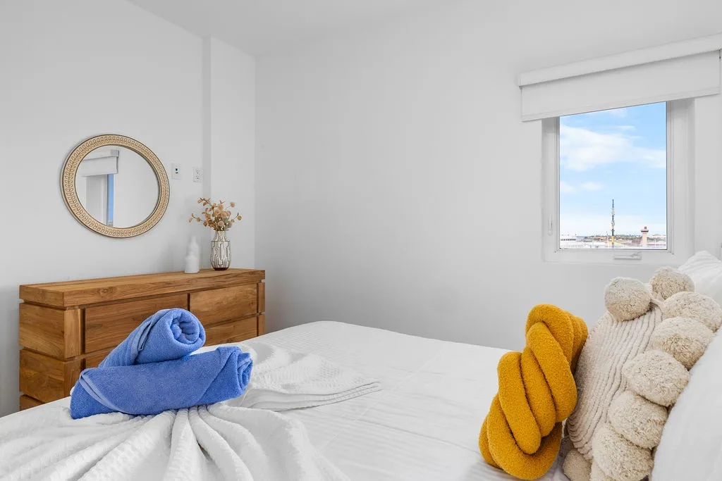 Sink into crisp white linens with cheerful accent towels and enjoy bright natural light streaming through your window. A peaceful space where your rest is the priority.