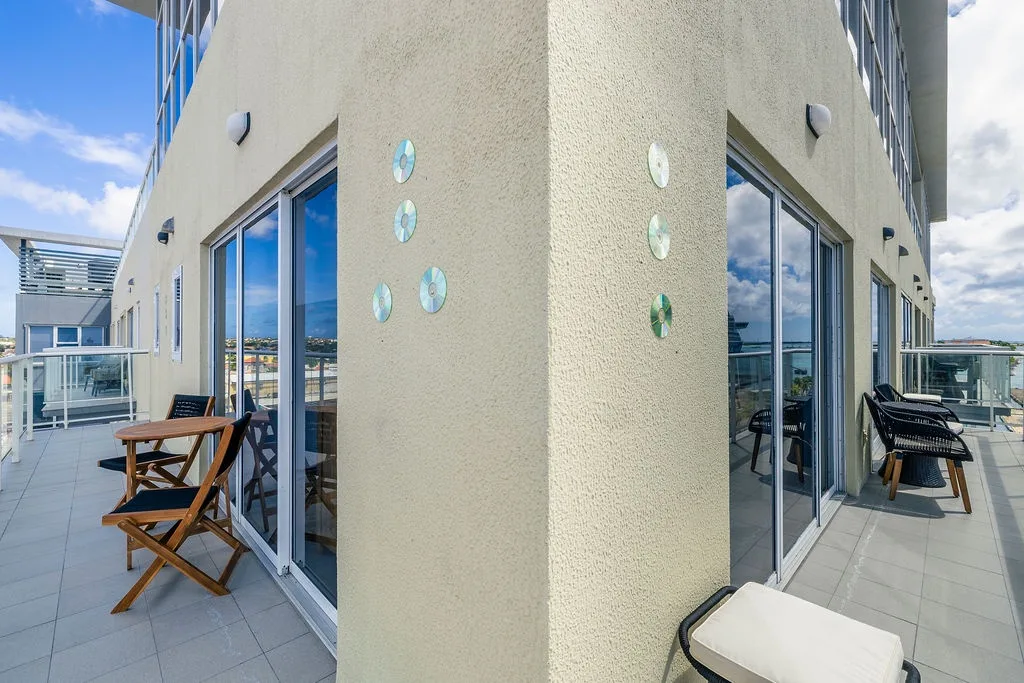 Modern corner balcony wraps around your space with sunny seating areas and playful sea-themed wall art, perfect for enjoying open-air breakfasts or evening cocktails under the sky.
