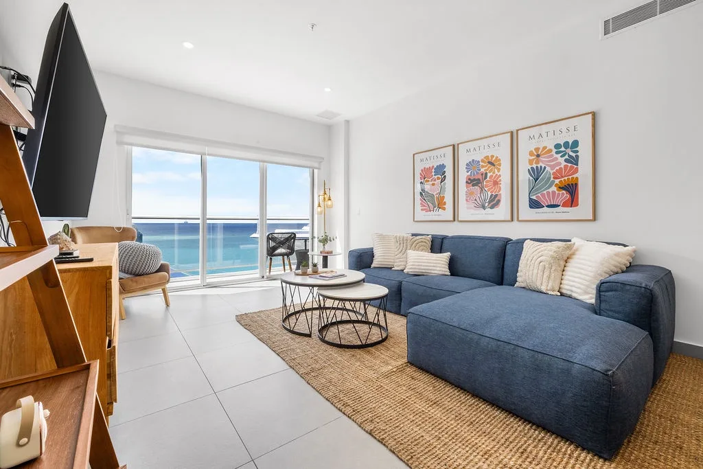 Your bright living space opens to endless ocean views, with plush seating, coastal artwork, and glass doors inviting sea breezes and relaxation.