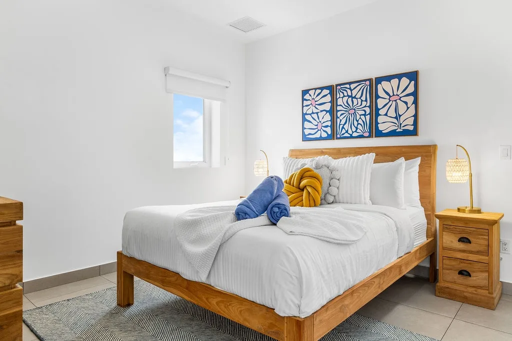 Sink into soft white linens and plush pillows after a day of exploring. Your bright, coastal-inspired bedroom offers peaceful relaxation with warm wood tones and calming blue accents.