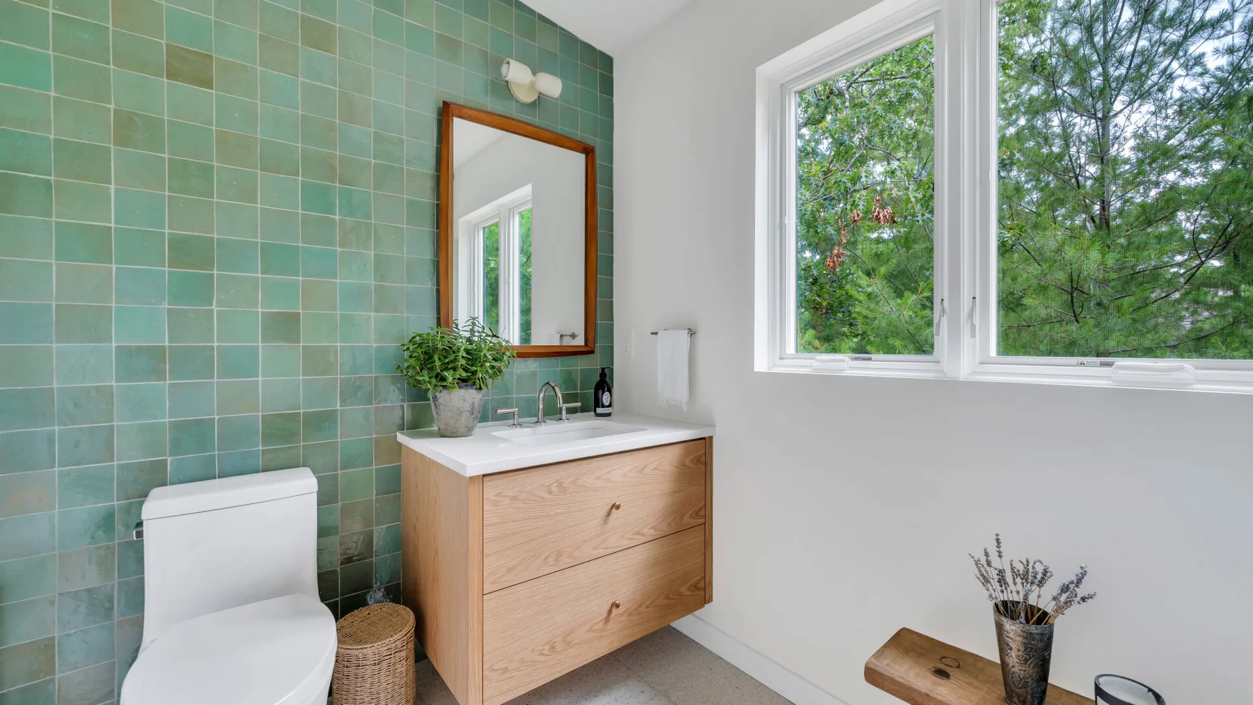 Un baño con un mueble de madera y una ventana grande con vista a los árboles.