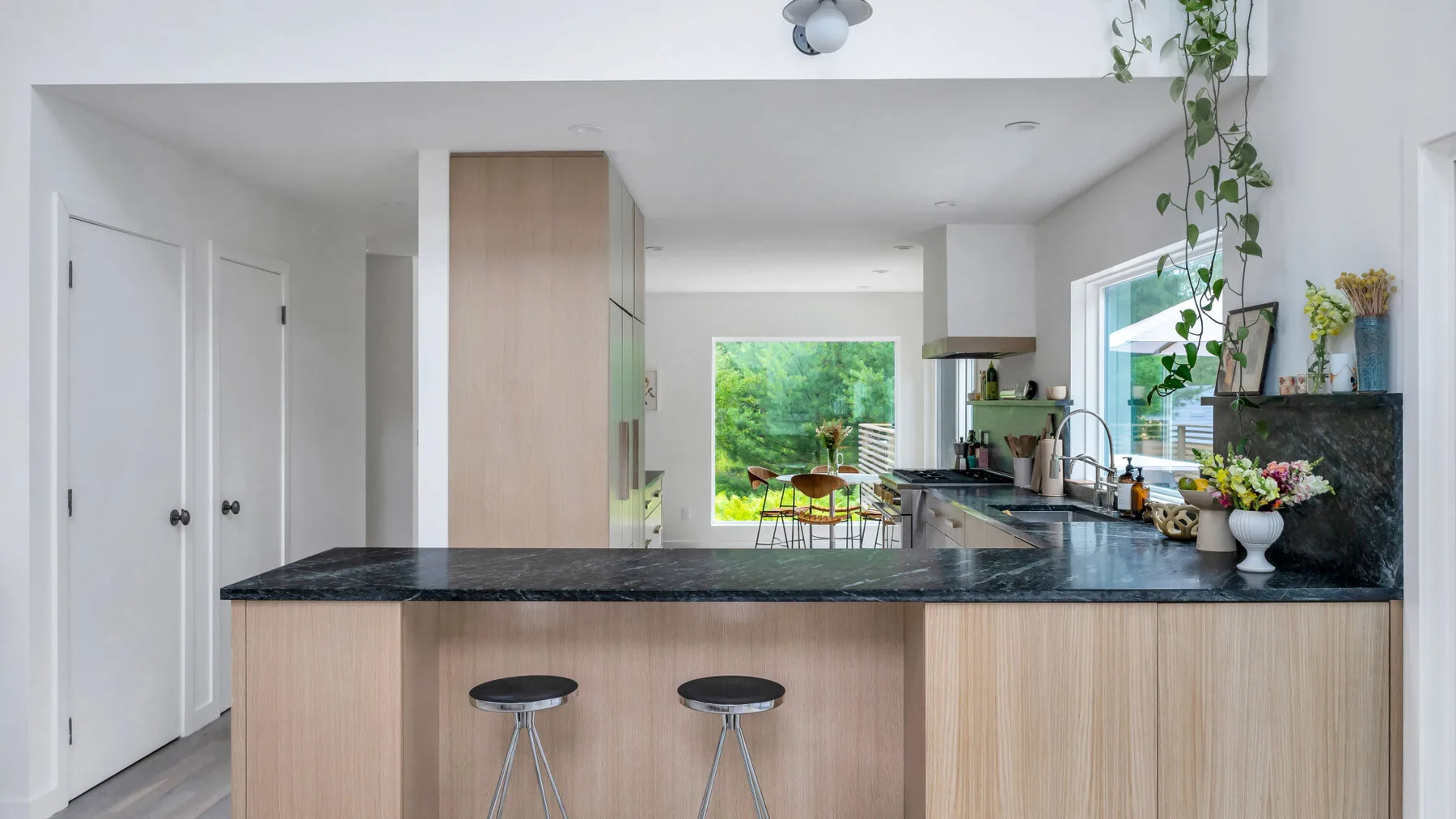 Una cocina luminosa con una isla larga y un comedor al fondo.