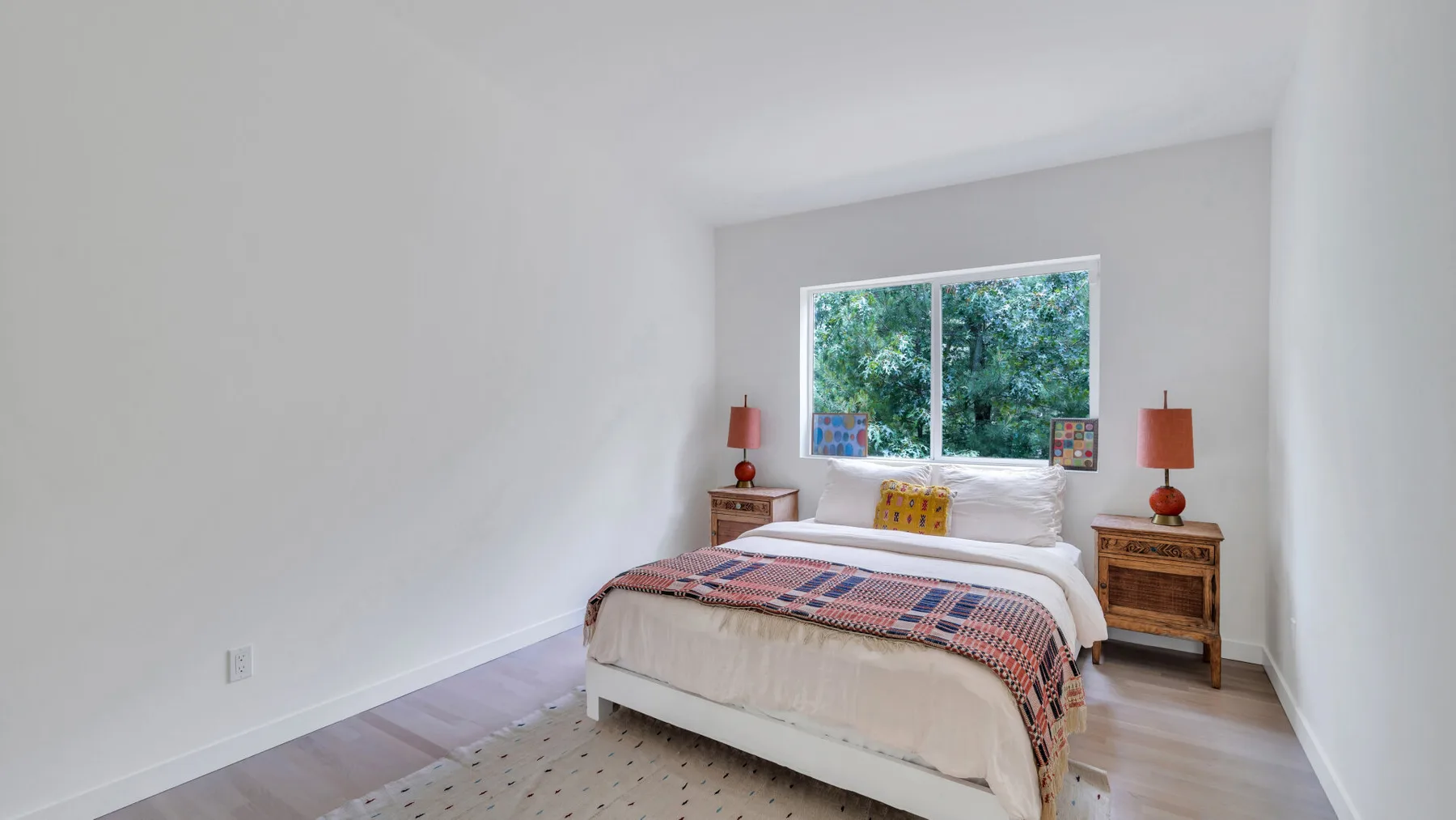 Un dormitorio luminoso con una cama bajo una ventana amplia.