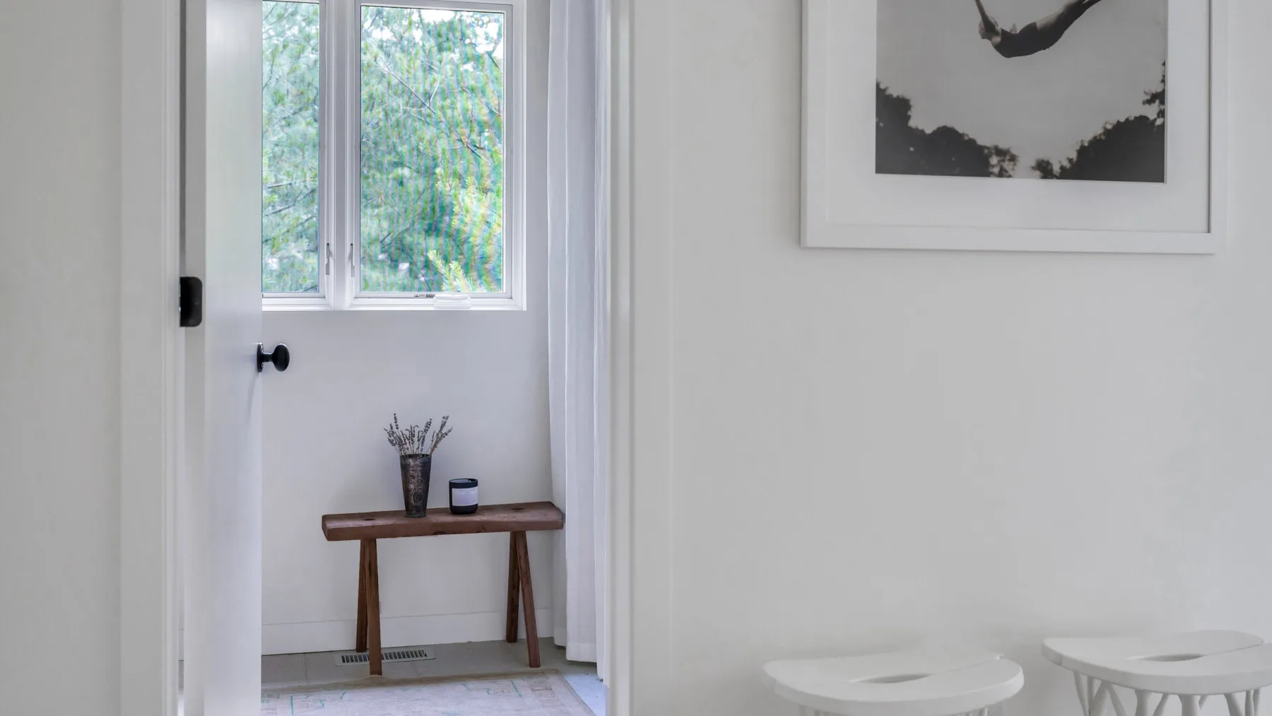 Un interior luminoso con una ventana, una mesa pequeña y asientos redondos.