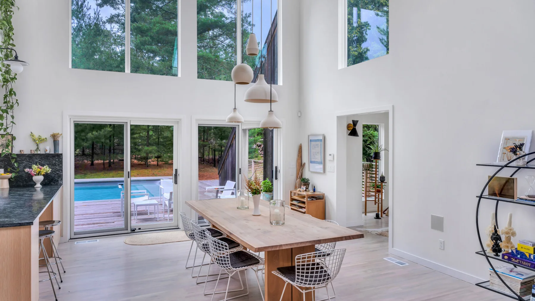 Una luminosa y amplia zona de estar y comedor con grandes ventanas que dan a una piscina.