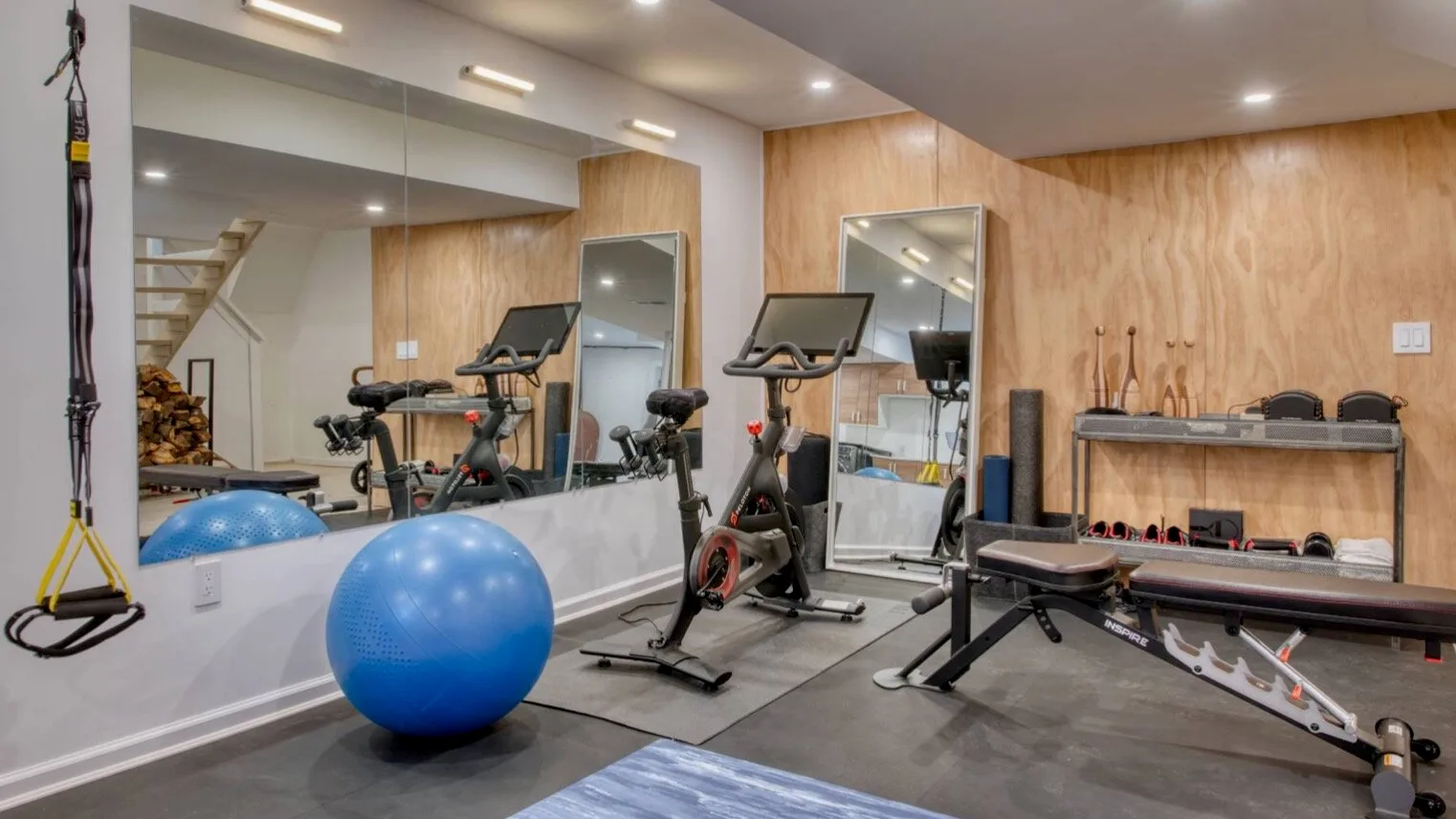 Un gimnasio con bicicletas estáticas, un banco de pesas y una pelota azul de ejercicio.