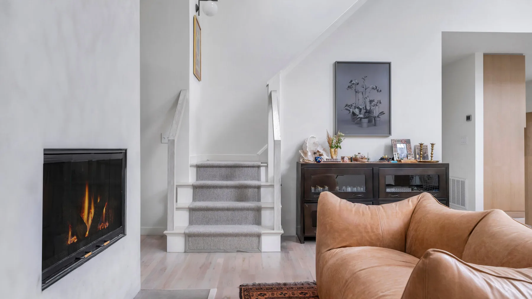 Una sala de estar con chimenea, escalera y asientos.