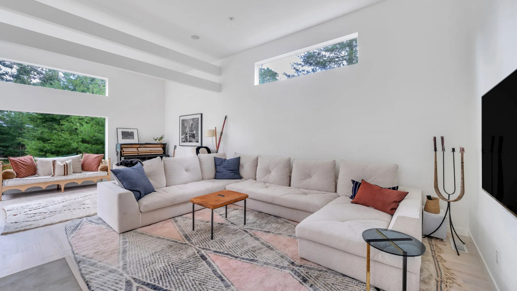 Una sala luminosa con asientos seccionales y ventanas grandes.