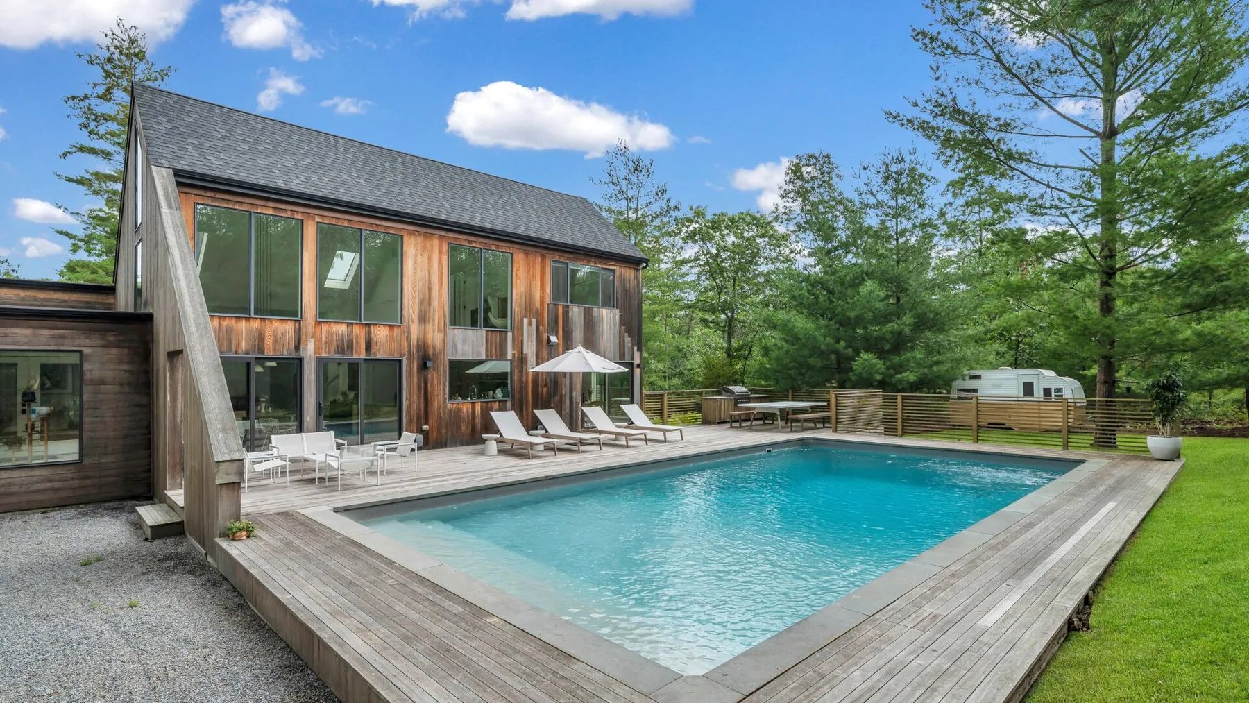 Una casa moderna está junto a una piscina y una terraza de madera.