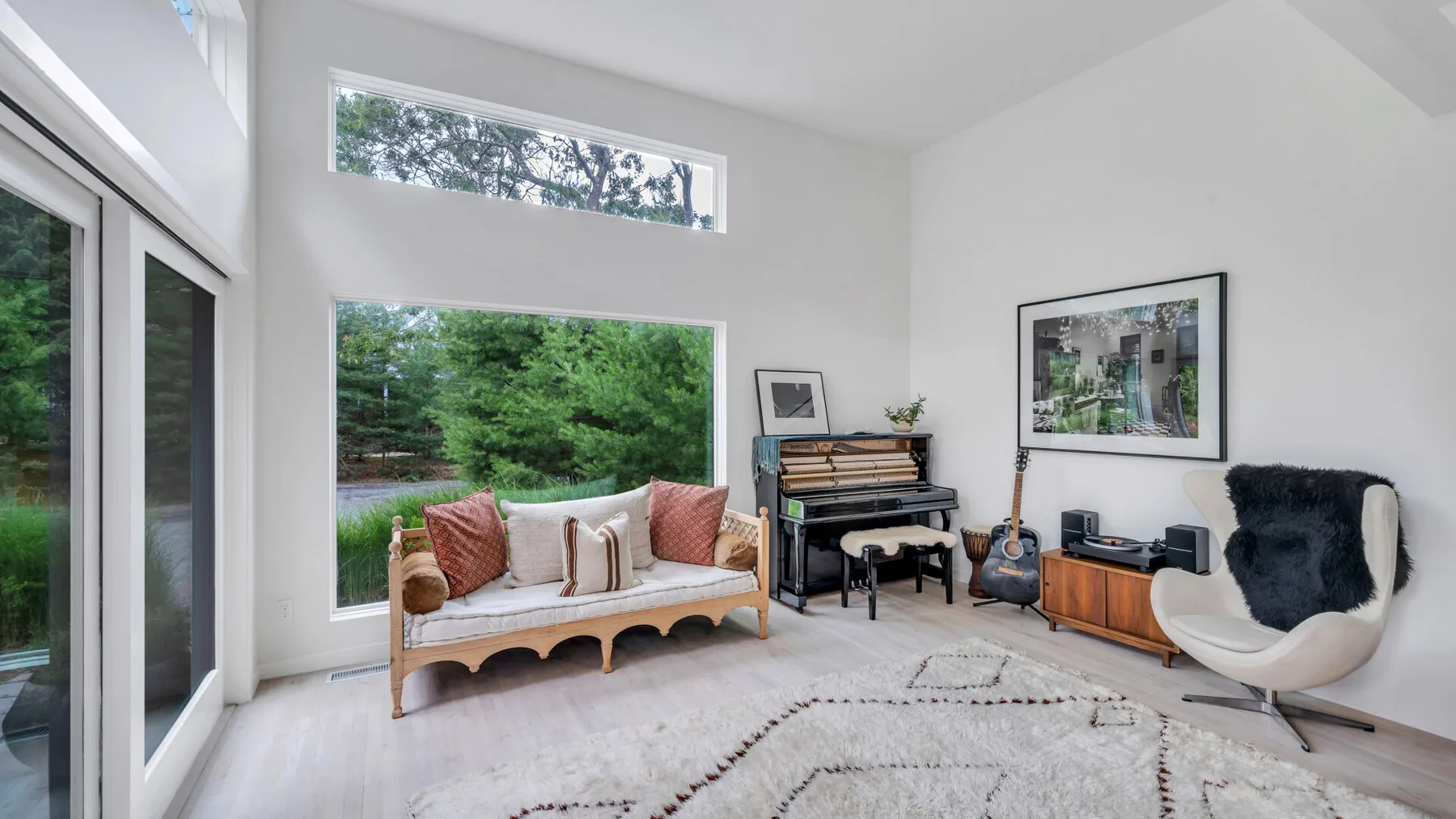 Una sala luminosa con una zona de asientos acolchados y un piano.