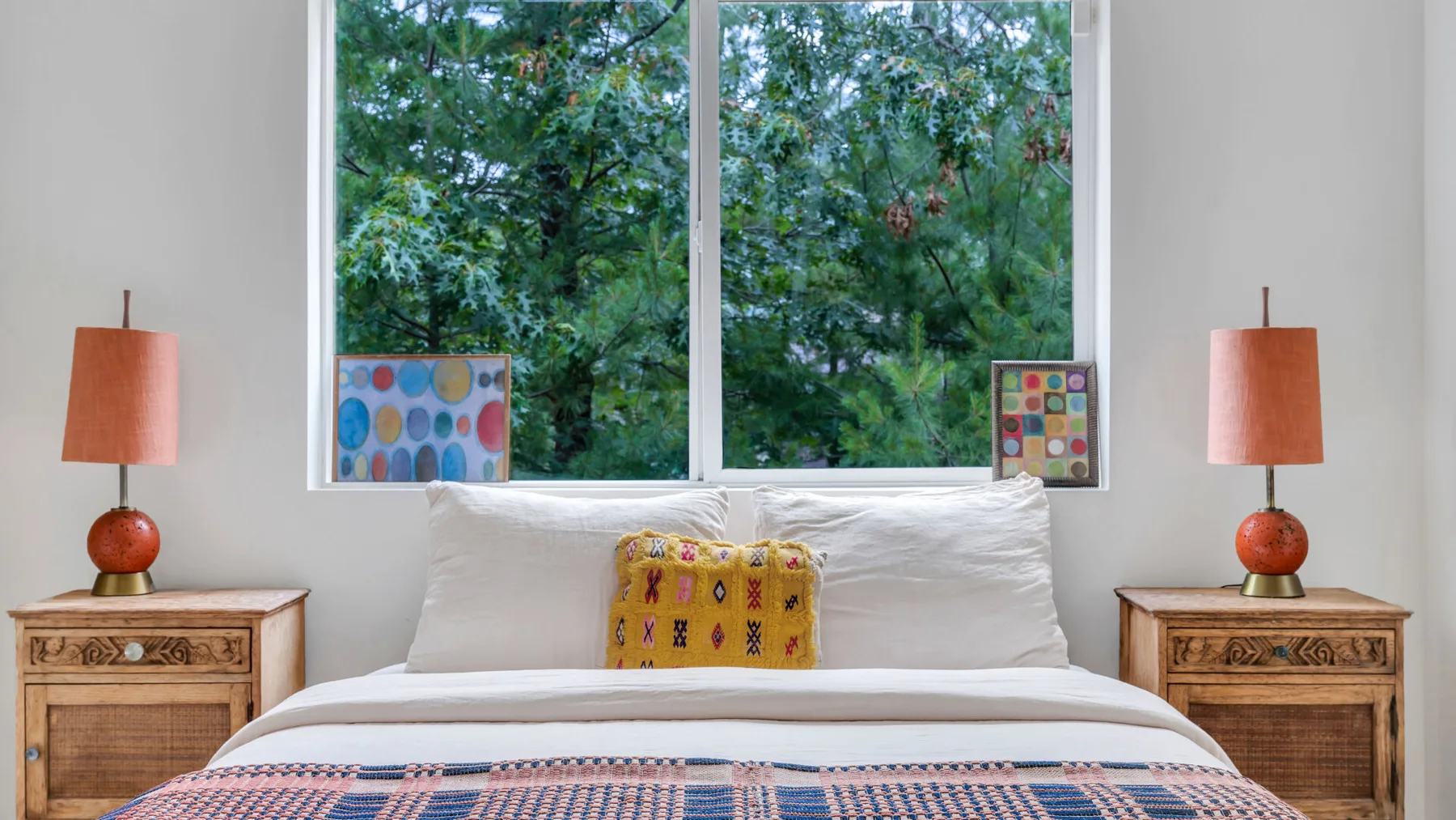 Un dormitorio con una cama bien arreglada bajo una ventana grande.