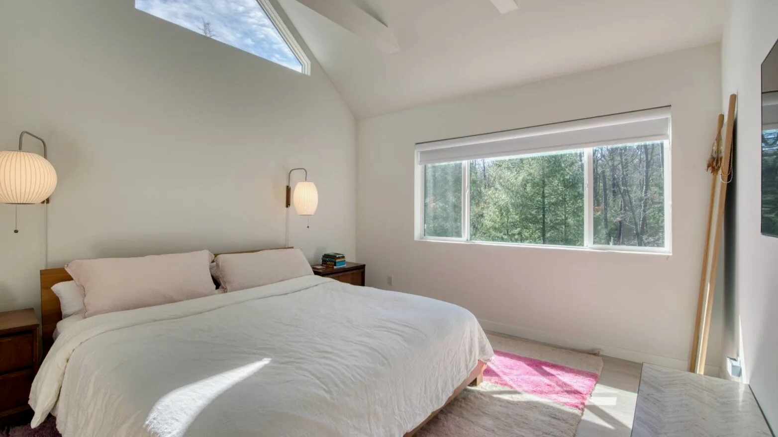 Un dormitorio luminoso con una cama grande junto a una ventana amplia.