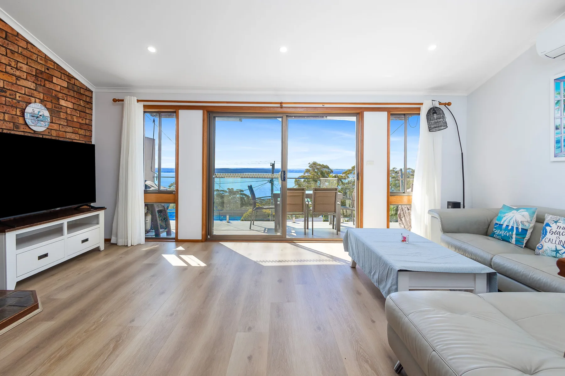 Una sala de estar con asientos y amplios ventanales con vistas al agua.