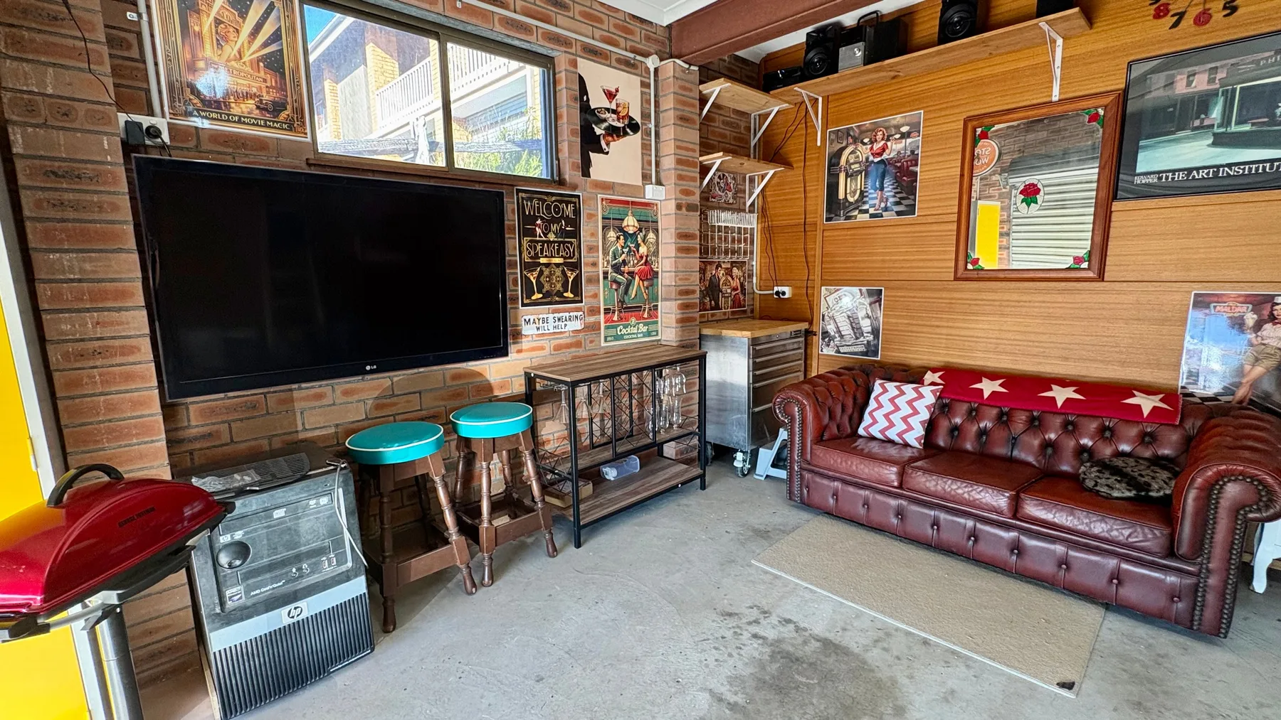 Una sala de estar con sofá de cuero, televisor y cuadros en las paredes.