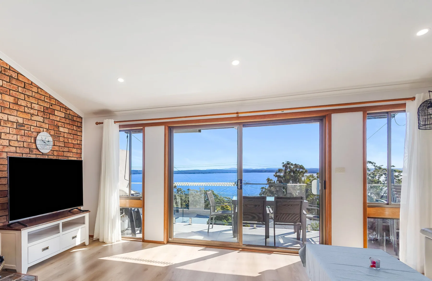 Sala de estar con puertas corredizas de vidrio que dan a un balcón con vistas al agua.