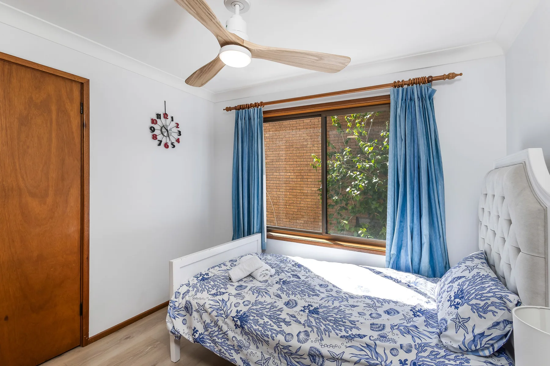 Un dormitorio con una cama bajo una ventana enmarcada por cortinas azules.