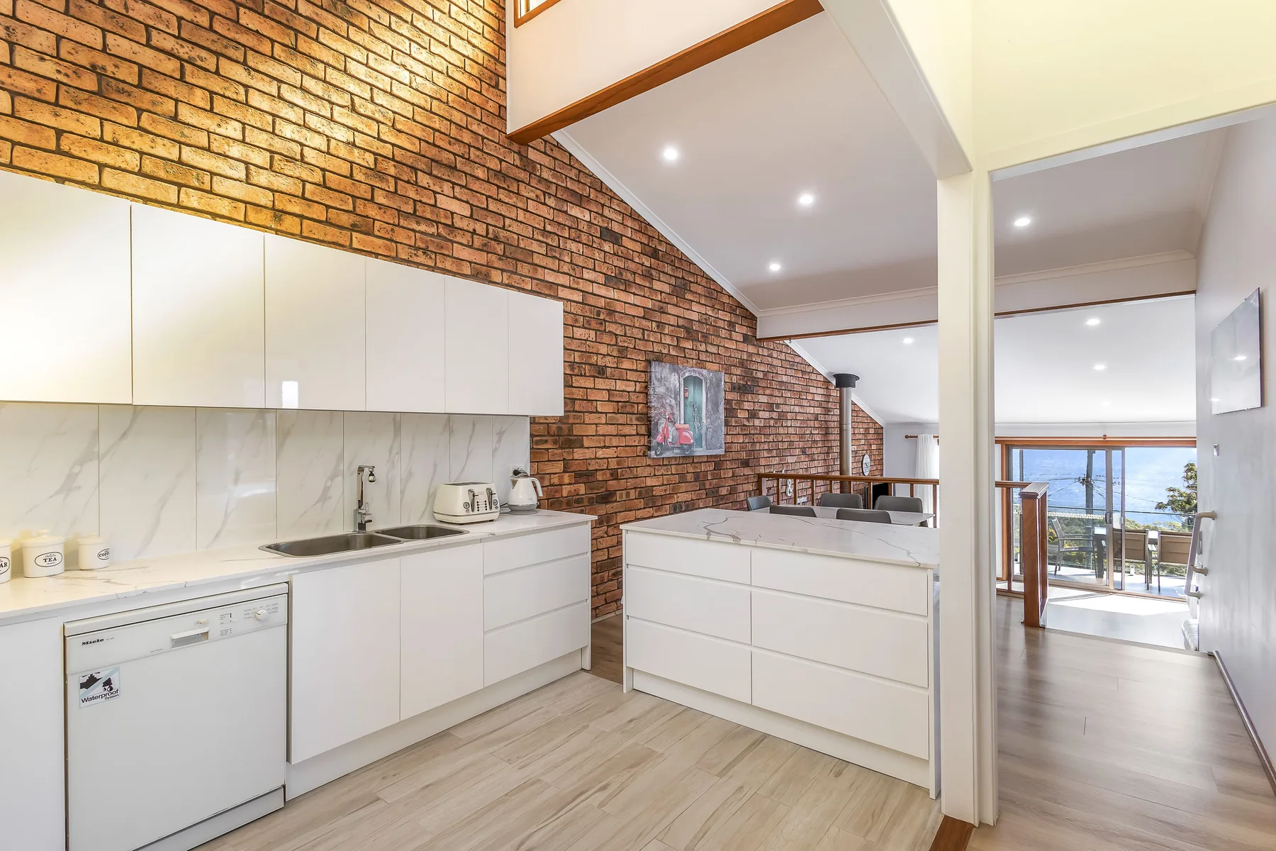 Una cocina moderna con armarios blancos y una pared de ladrillo.