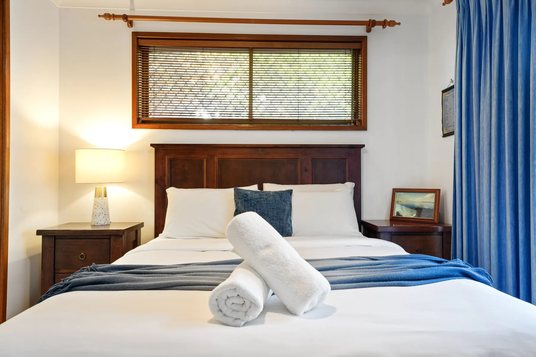 Un dormitorio con una cama bien arreglada y cortinas azules.