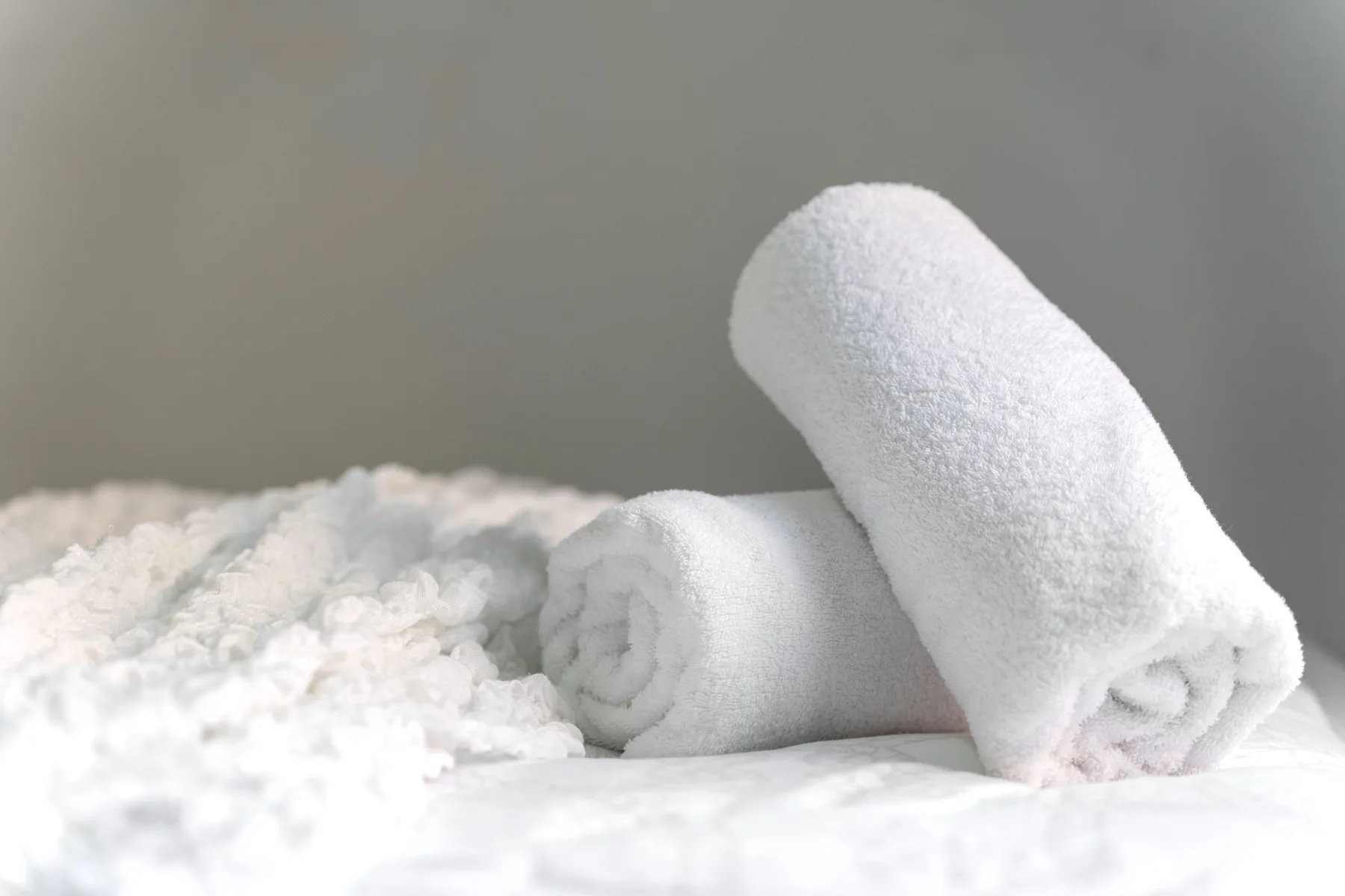 Una cama con toallas blancas dobladas sobre la ropa de cama.